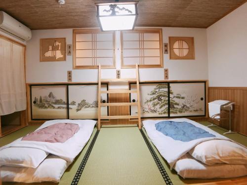 2 Betten in der Mitte eines Zimmers in der Unterkunft PittINN in Goshogawara