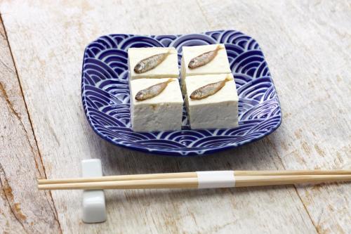 a piece of cake on a blue plate with chopsticks at Living Inn Asahibashiekimae Premier in Naha