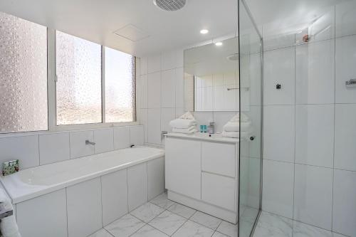 baño blanco con bañera y ducha acristalada en Dorchester On The Beach, en Gold Coast