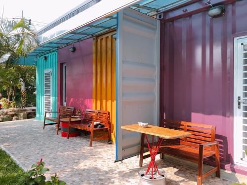 a patio with benches and a table and a building at Little Ryukyu Hermit Crab Homestay in Xiaoliuqiu