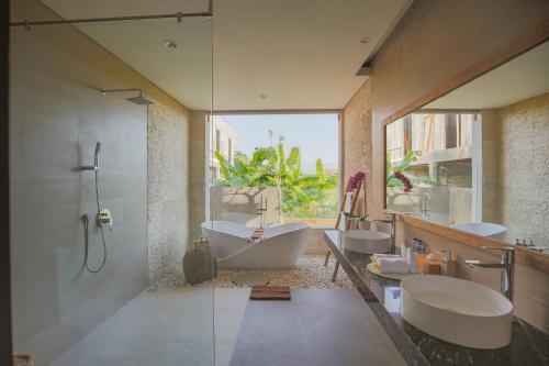 een badkamer met 2 wastafels en een bad bij Uwu Villas in Canggu