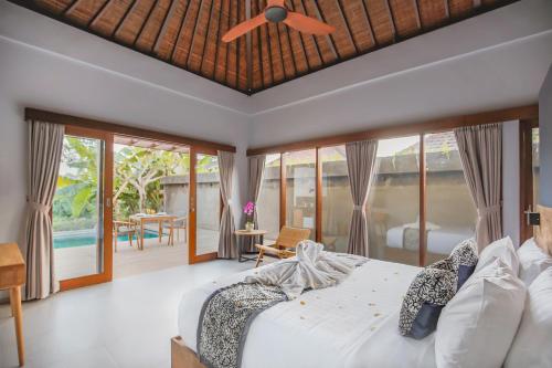 een slaapkamer met een bed en een plafondventilator bij Uwu Villas in Canggu