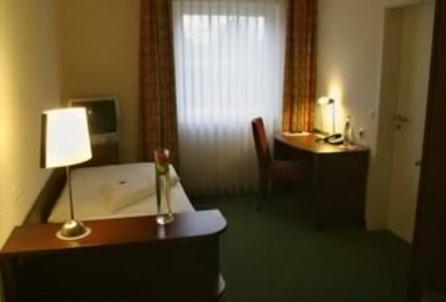 a hotel room with a desk and a lamp and a room at Hotel Auerhahn in Pulheim