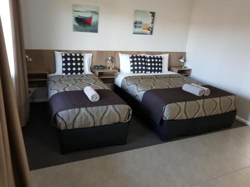 a hotel room with two beds in a room at Main Street Motel in Hervey Bay