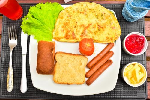 a plate of breakfast food with eggs sausage and bread at Peacock Beach Hotel Unawatuna in Unawatuna