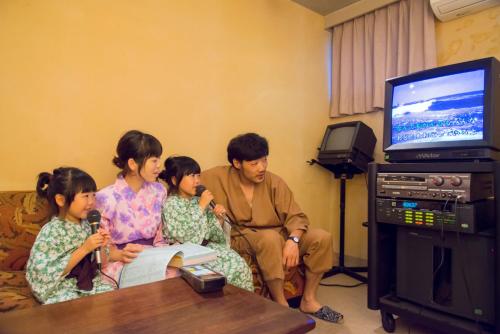 a family sitting in a living room with a television at Ichirino Kogen Hotel Roan in Hakusan