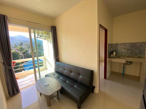 a living room with a couch and a table and a window at Budchui Guesthouse in Koh Tao