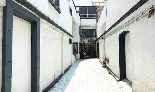 un callejón vacío con dos edificios blancos y una puerta en Terraza Tlalpan-Acoxpa, en Ciudad de México