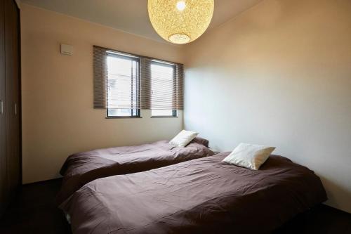 a bedroom with two beds and a chandelier and two windows at Chie's house in Mitaka