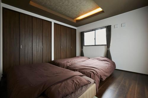 a bedroom with two beds and a window at Chie's house in Mitaka