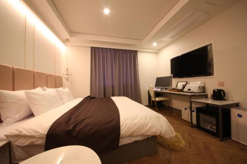 a hotel room with a bed and a desk with a computer at Den Basta Hotel in Busan