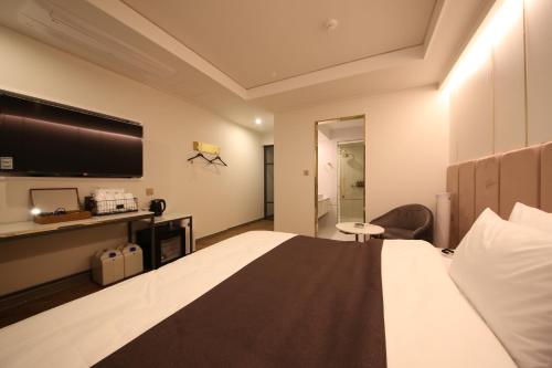a hotel room with a bed and a flat screen tv at Den Basta Hotel in Busan