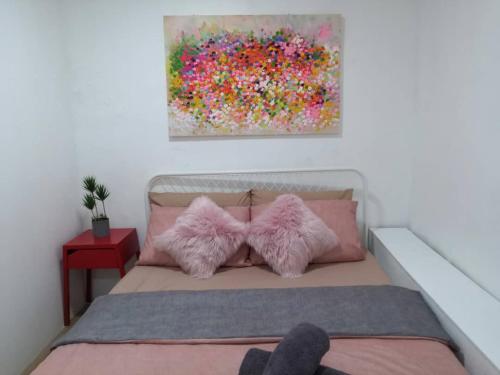 a bedroom with a bed with pink pillows and a painting at Malacca Jonkerhouse in Melaka
