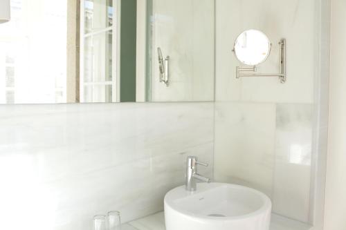 Baño blanco con lavabo y espejo en Hotel Pazo de Altamira, en Santiago de Compostela