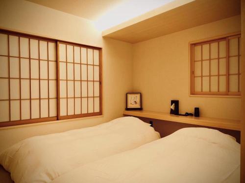a bedroom with two white beds and two windows at Ishibekoji Muan in Kyoto