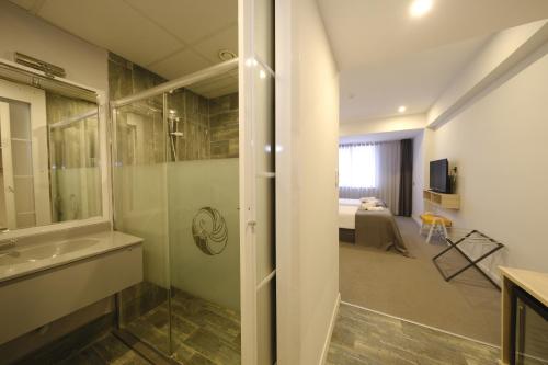a bathroom with a shower and a sink and a bedroom at leto city hotel in Eskisehir