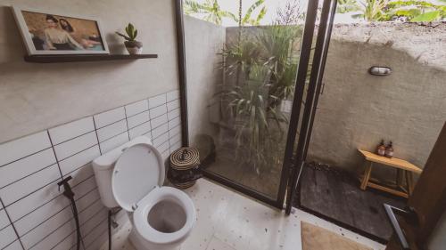a bathroom with a toilet and a glass shower at Little Ripper Boutique Lofts in Tanah Lot