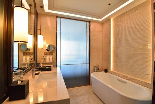 a bathroom with a large tub and a sink at Vignette Collection Haikou Yatter Hotel by IHG in Haikou