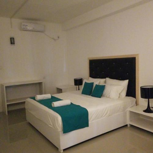 a bedroom with a large bed with green and white pillows at One World Mirissa in Mirissa