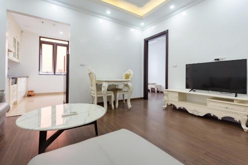 a living room with a flat screen tv and a table at The Peninsula Haiphong in Hai Phong