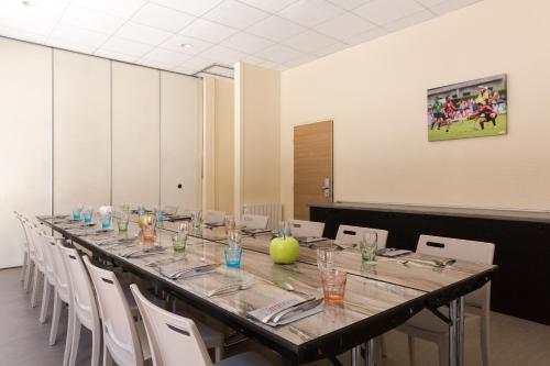 a long long table in a room with white chairs at Logis Hôtel du Haut-Bugey in Oyonnax