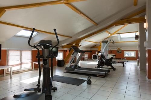 a gym with treadmills and exercise bikes in a room at Hôtel Central Parc Oyonnax in Oyonnax