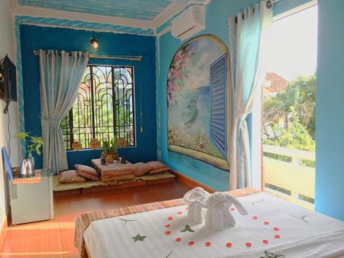 Cette chambre bleue comprend un lit et une fenêtre. dans l'établissement Longan Homestay, à Hội An