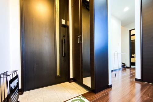 a hallway with two black doors and a wooden floor at Yahiro 4-chome House 2F,3F in Tokyo