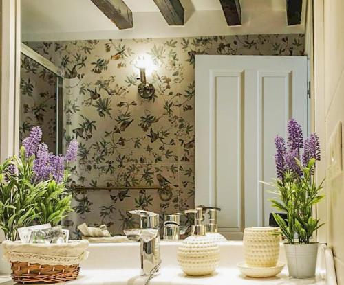 baño con lavabo con espejo y flores púrpuras en Tres Lunas, en Toledo