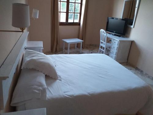 - une chambre avec un lit blanc et une télévision dans l'établissement Hotel Anfiteatro Romano, à Santiponce