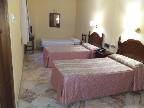 
a hotel room with two beds and two lamps at Hotel Anfiteatro Romano in Santiponce

