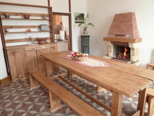 a kitchen with a wooden table and a fireplace at Gîte Meublé in Anost