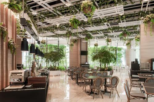 a restaurant with tables and chairs and plants on the ceilings at Komune Living in Kuala Lumpur