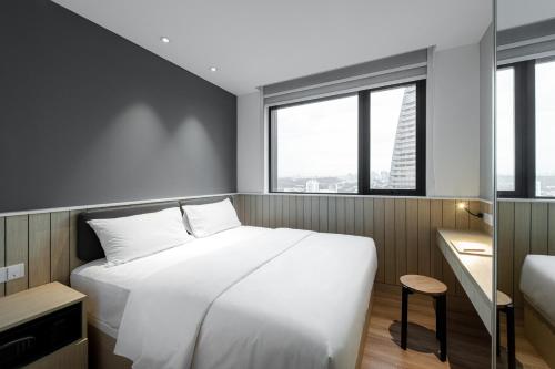 a bedroom with a large white bed and windows at Komune Living in Kuala Lumpur