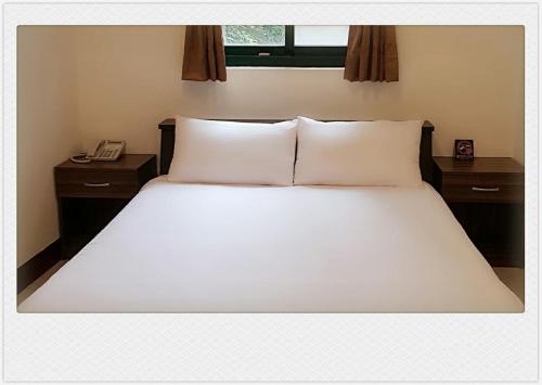 a bed with white sheets and pillows in a bedroom at Jiou Wu Siao Jhu in Nangan