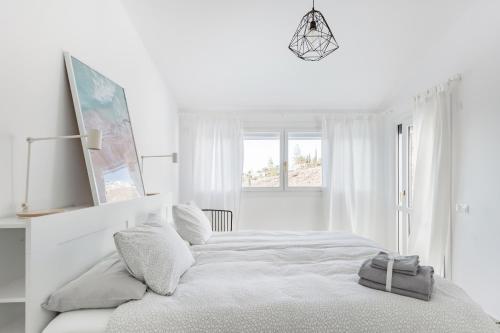 a white bedroom with a large bed and a window at Sea view villa San Agustin vista Claveles in San Agustin