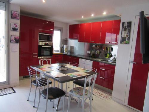 une cuisine avec des armoires rouges et une table et des chaises dans l'établissement Appartement Grand Calypso, à Frontignan