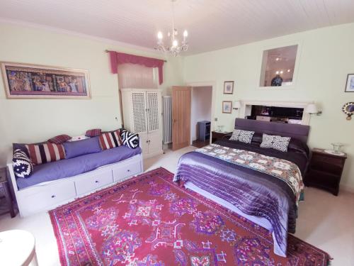 a bedroom with a bed and a couch and a rug at Leithen Lodge in Innerleithen