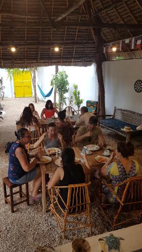 a large group of people sitting around a table at Wakanda Hotel in Nungwi