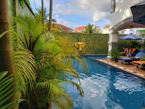 a swimming pool with palm trees next to a fence at Parent Heritage Angkor Villa in Siem Reap