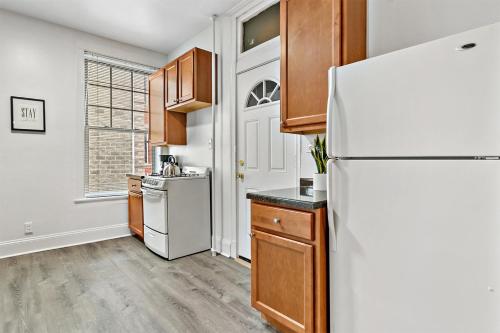 a kitchen with a white refrigerator and wooden cabinets at Cool 2BR Apartment close to Fun City - Grace 2 in Chicago