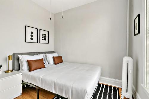- une chambre avec un lit doté de draps blancs et d'oreillers orange dans l'établissement Cool 2BR Apartment close to Fun City - Grace 2, à Chicago