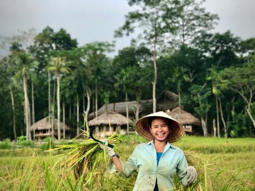 a woman wearing a hat holding a bunch of grass at Lua Pu Luong in Pu Luong