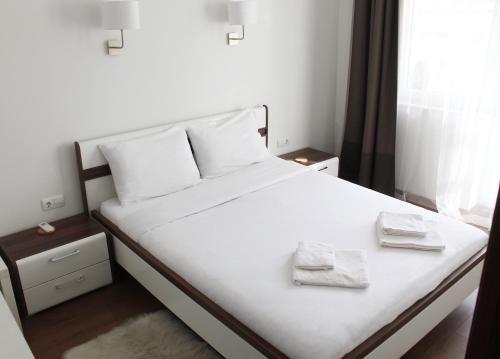 a bedroom with a white bed with two towels on it at Super Central Luxury Apartments in Burgas City