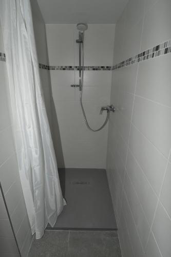 La salle de bains blanche est pourvue d'une douche avec rideau de douche. dans l'établissement Face Mont-Blanc, à Passy