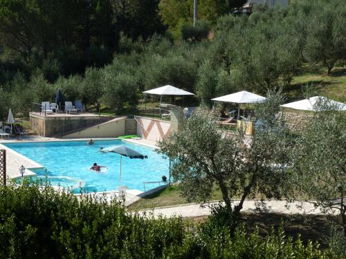 ein großer Pool mit Sonnenschirmen und Menschen darin in der Unterkunft Residence Il Monastero in Pomarance
