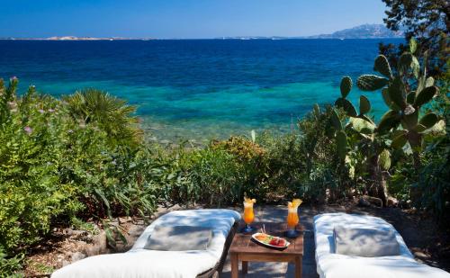 two chairs and a table with a view of the ocean at Hotel Capo d'Orso Thalasso & SPA in Palau