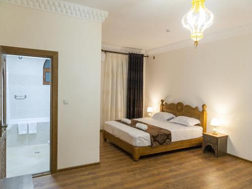 - une chambre avec un lit et un lustre dans l'établissement Royal Bukhara hotel, à Boukhara
