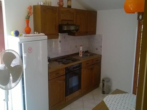 a kitchen with wooden cabinets and a white refrigerator at Bernie Apartments in Poreč