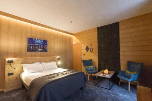 ein Schlafzimmer mit einem Bett und zwei blauen Stühlen in der Unterkunft Hôtel Astérides Sacca in Cauterets